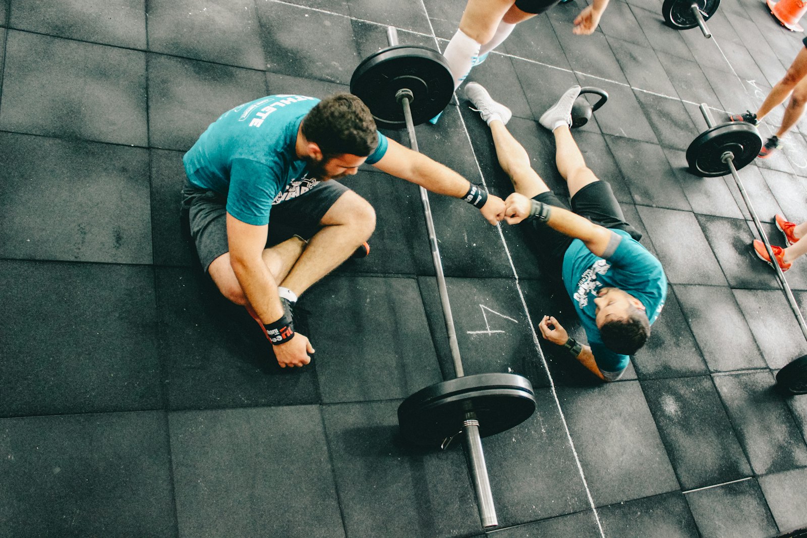 Two people fist-bumping on a gym floor between sets