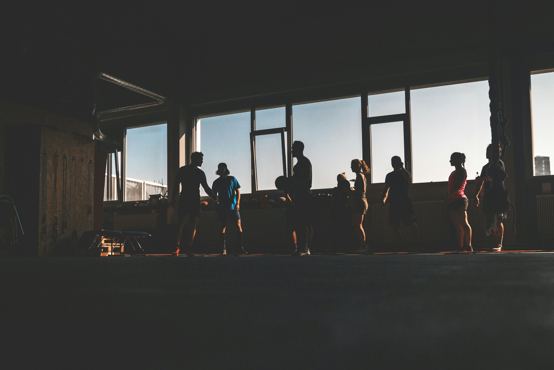 A small group silhouetted against gym windows at golden hour