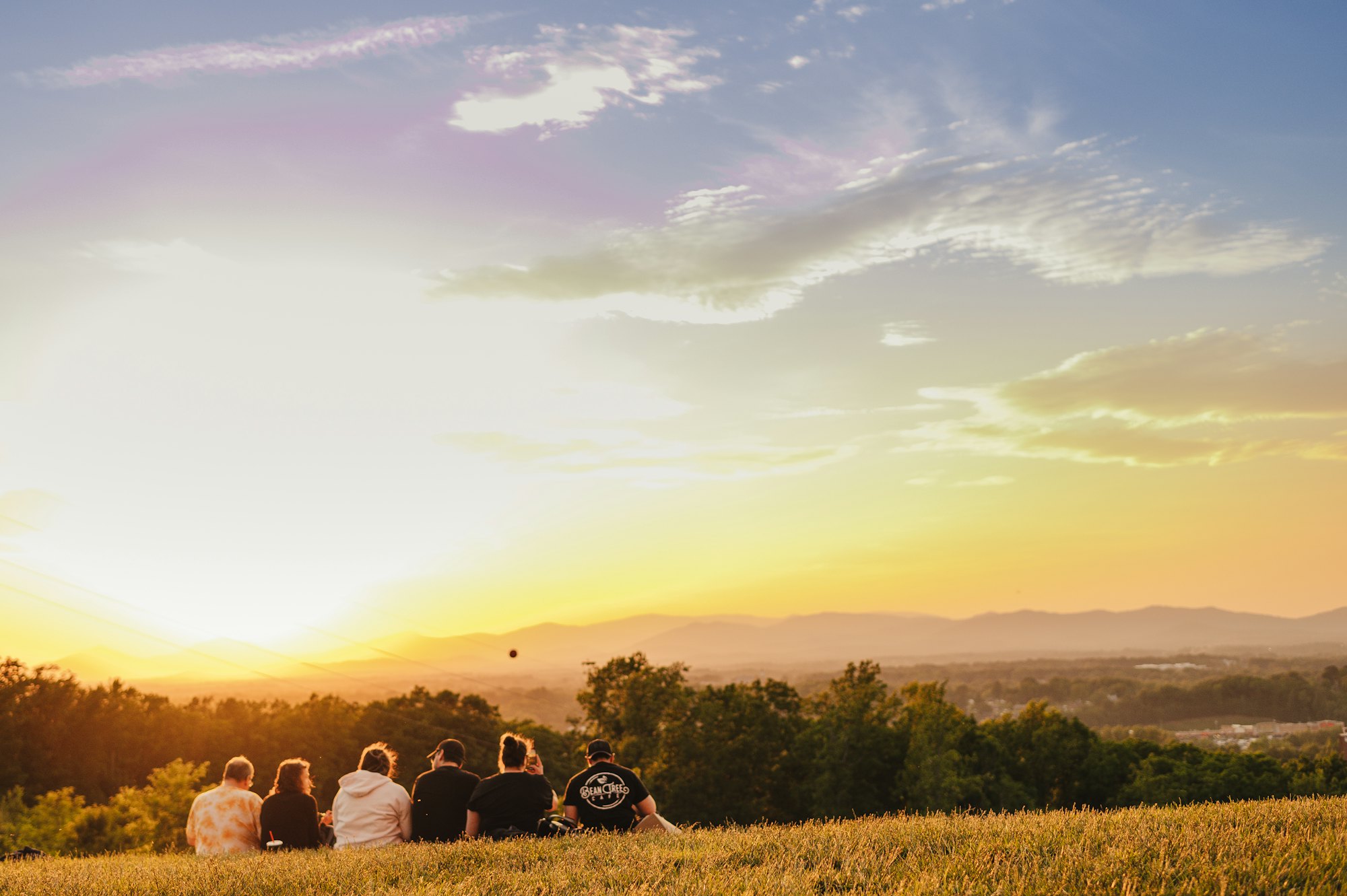 A small group sitting together on a hill at sunset