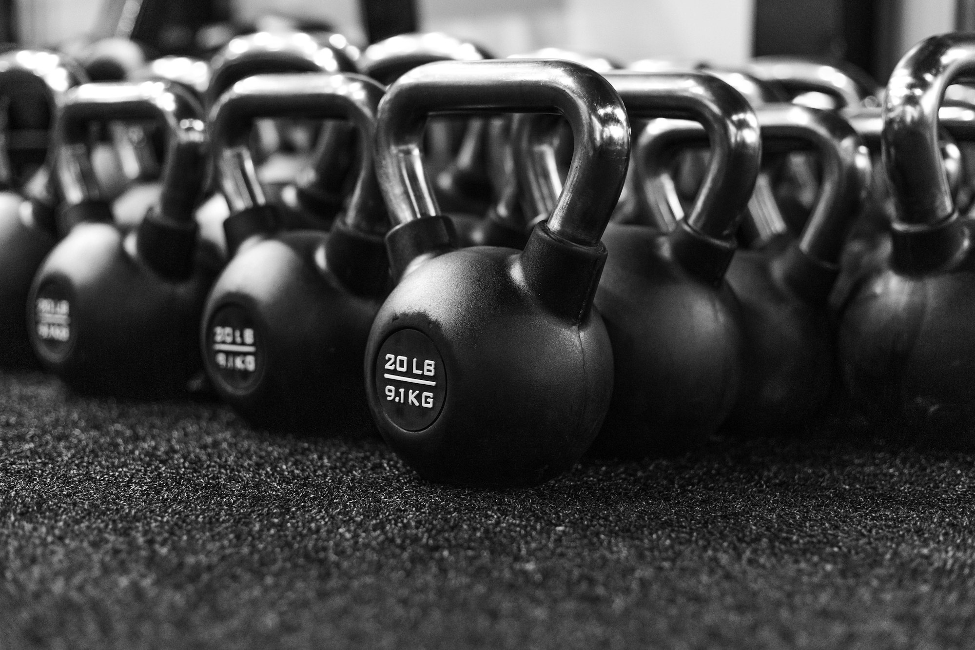 A row of kettlebells waiting on a gym floor