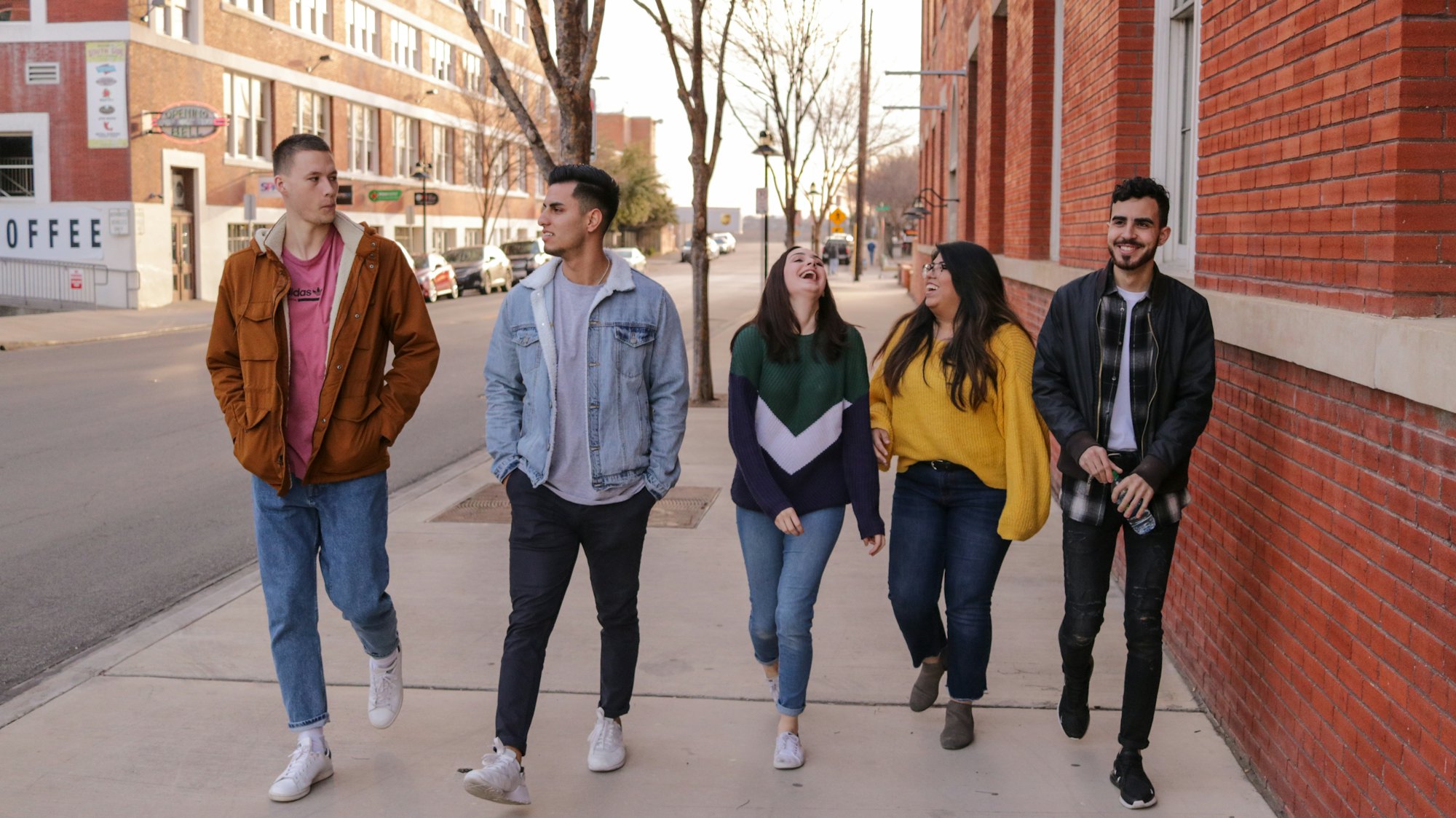 A group of friends walking down a street together, laughing