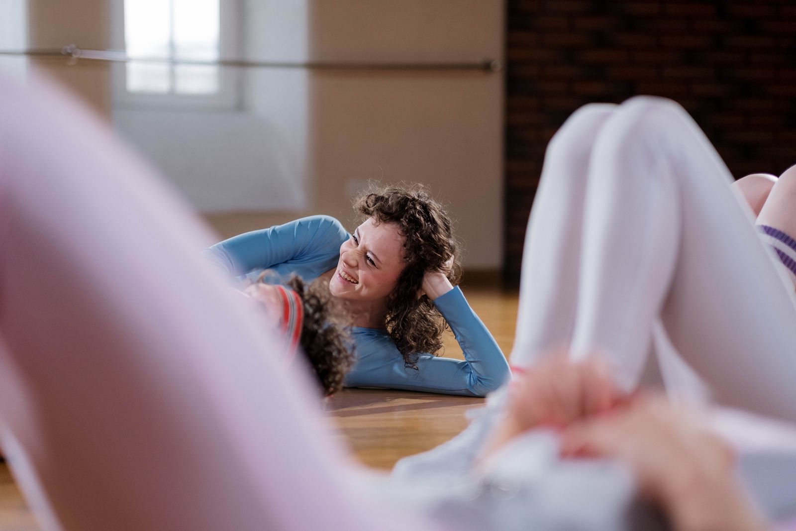 A woman laughing mid-crunch during a group class